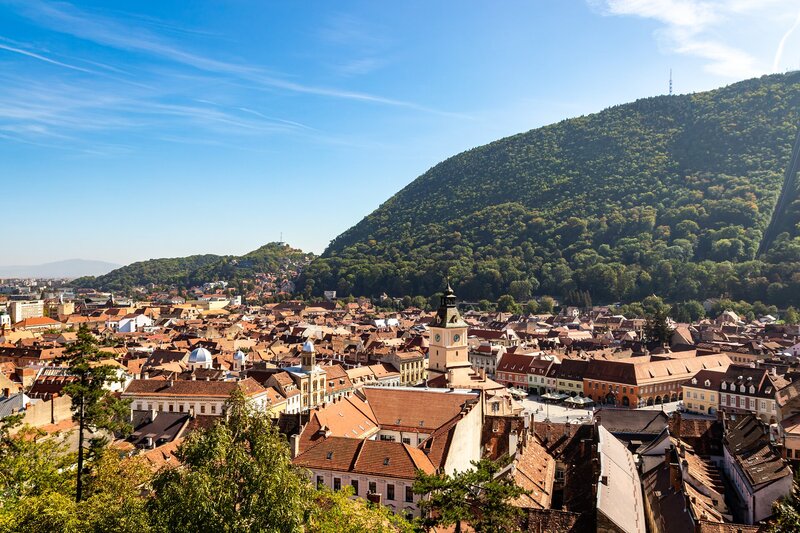 Blick über die roten Dächer der Altstadt von Brașov bis zum bewaldeten Tâmpa-Berg