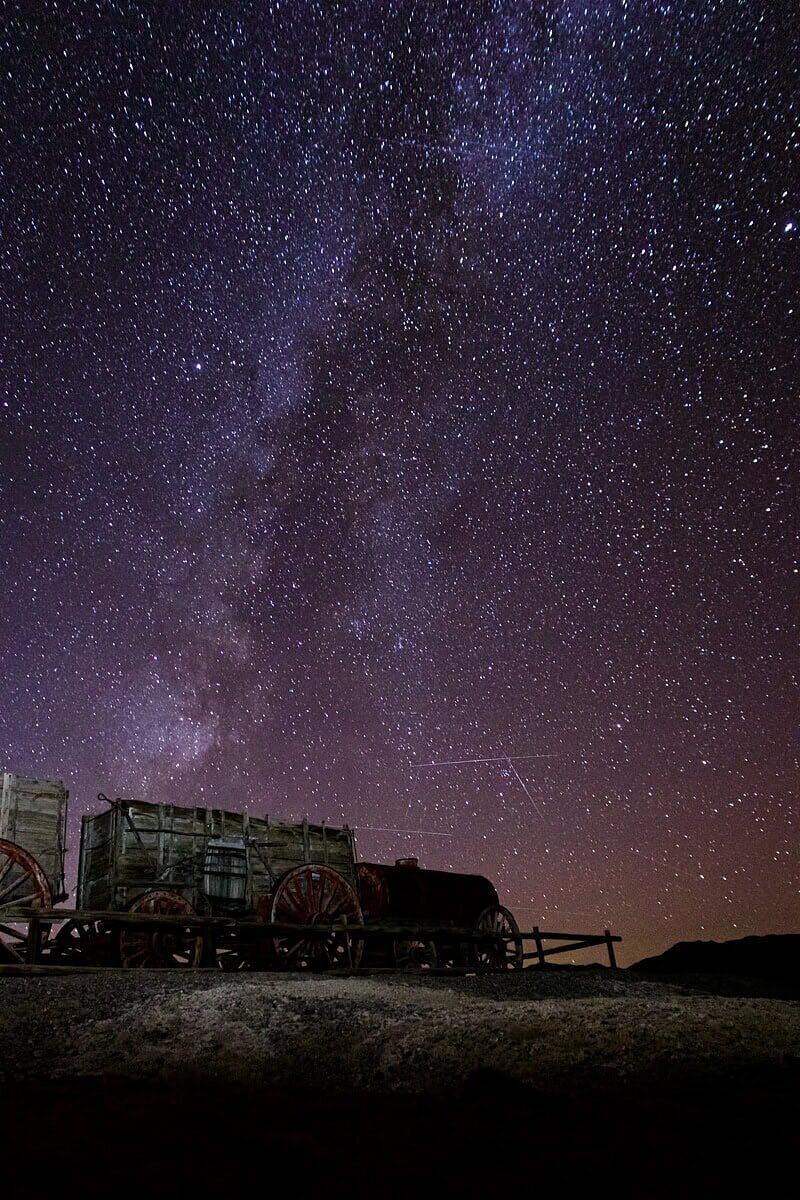 Die Milchstraße funkelt über einem historischen Planwagen im Death Valley