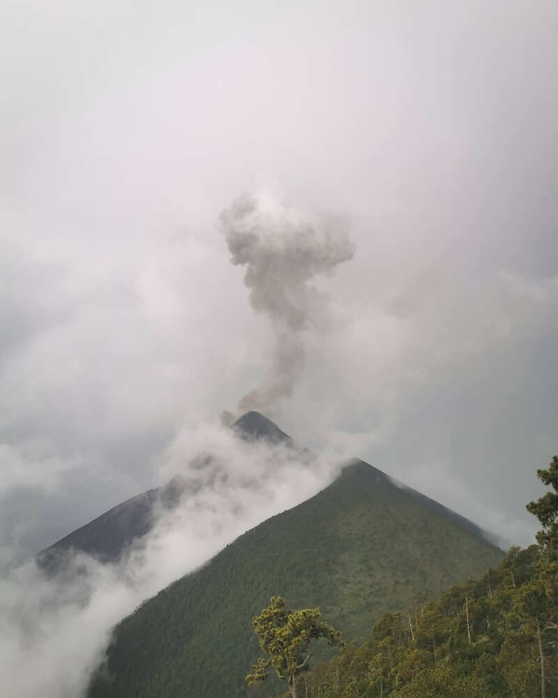 Der Fuego schickt eine Aschewolke in den Himmel, während die Wolken um den Gipfel tanzen