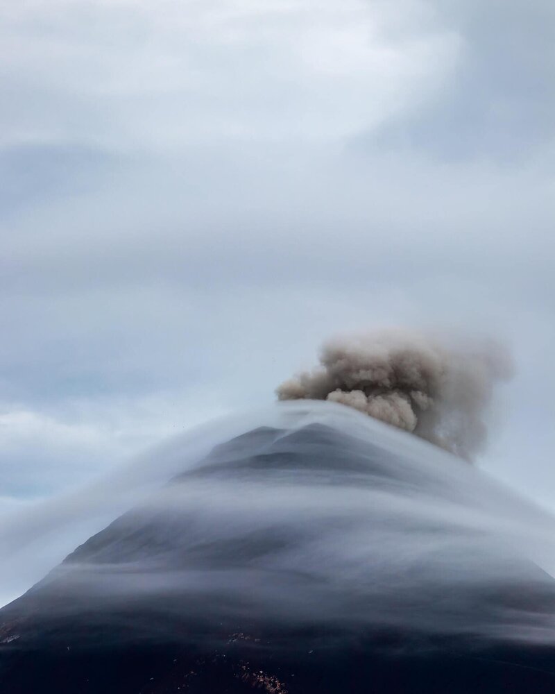 Eine Aschewolke steigt aus dem wolkenverhangenen Gipfel des Fuego auf